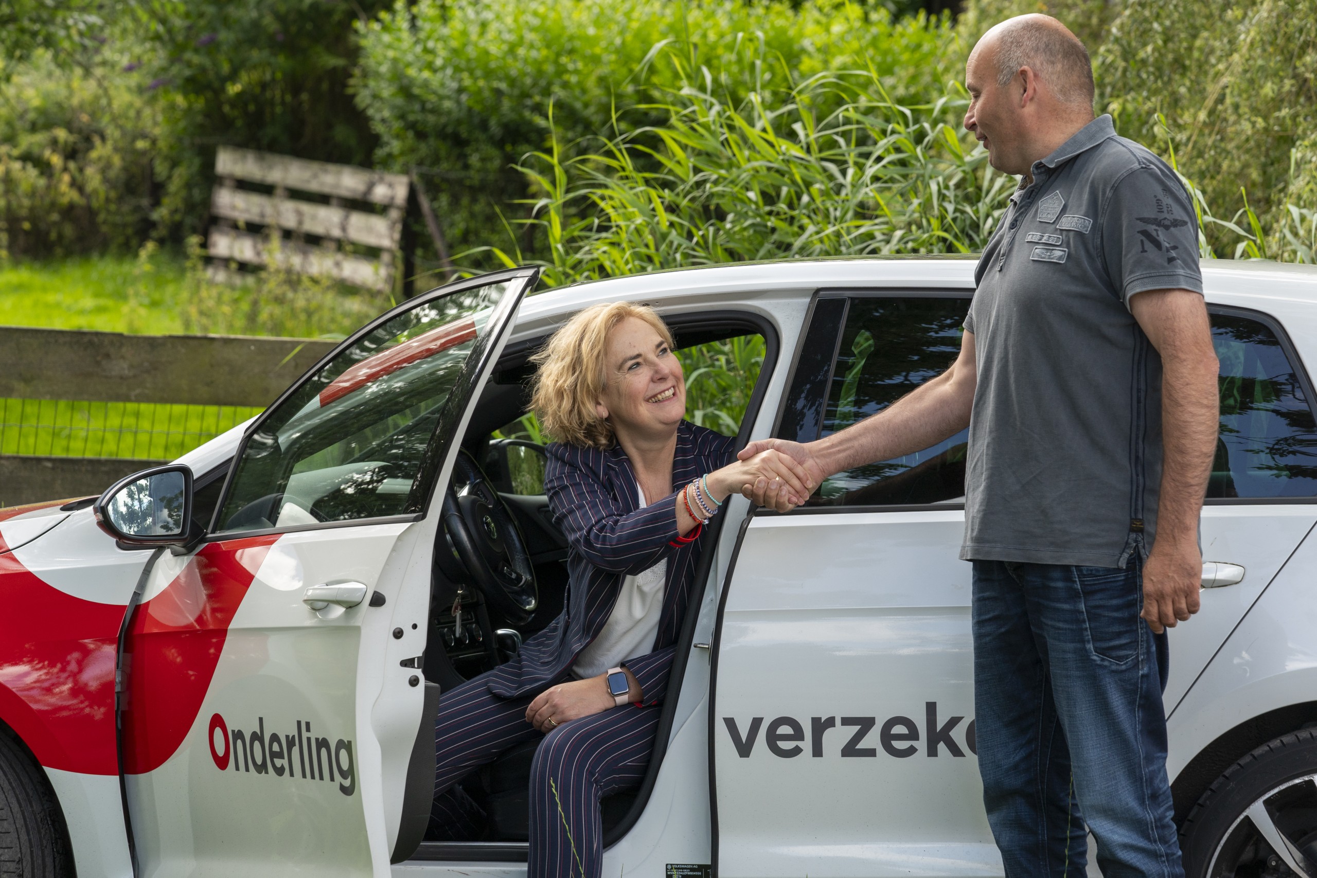 Klantadviseur stapt uit auto bij agrarische klant. Onderling Verzekerd