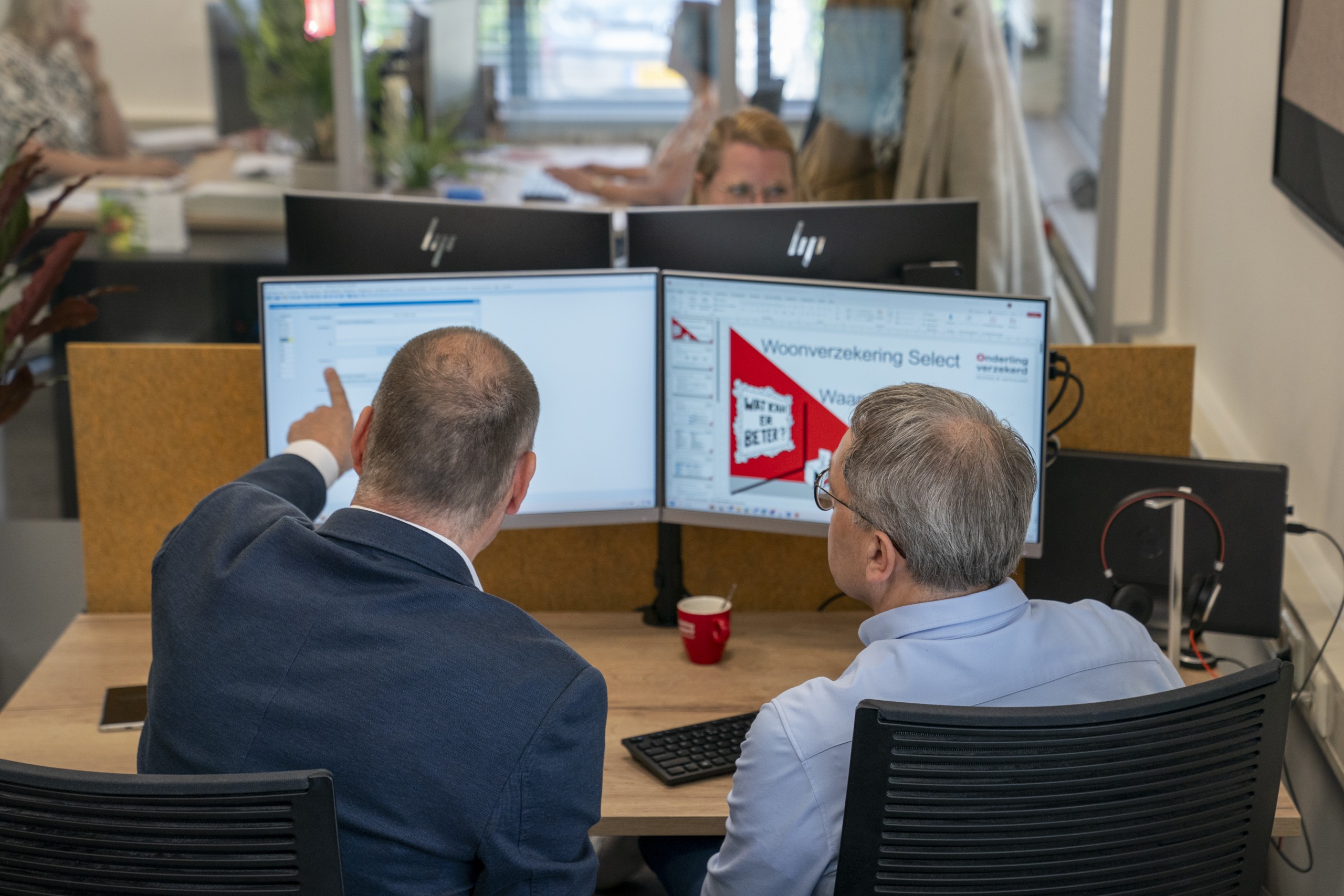 Twee mannen bekijken achter computerscherm de risico's van een klant. Onderling Verzekerd